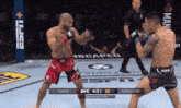 two men are fighting in a boxing ring with a referee in the background .
