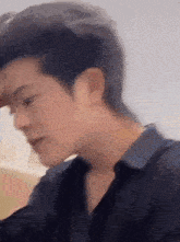 a close up of a man 's face with a blurry background . he is wearing a black shirt .