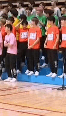 a group of people wearing orange shirts with numbers on them