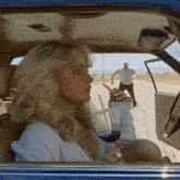 a woman in a car with a glass of wine