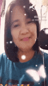 a woman wearing a blue shirt is smiling and has a butterfly on her shirt