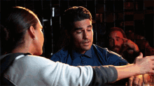 a man in a blue shirt is talking to a woman in a white sweater