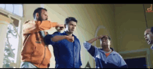 a group of men are standing in a room and one of them is wearing an orange sweatshirt that says ' nba '