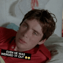 a man in a red shirt is laying on a bed with a sticker that says even he was weirded tf out