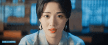 a close up of a woman 's face with a blue banner behind her that says ' a ' on it