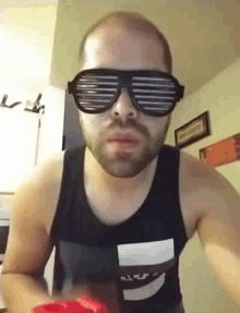 a man with a beard wearing sunglasses and a tank top that says nyp