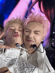 a man with pink hair is kissing another man