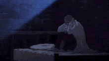 a man sits on a bed with his head down