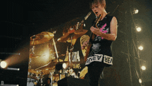 a man playing a guitar in front of a sign that says " new bea " on it