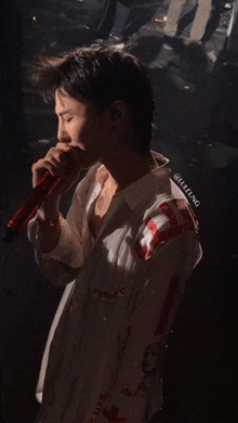 a man singing into a microphone with a white shirt that says ' supreme ' on it