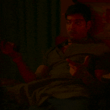 a man is laying on a bed in a dark room and talking on a phone .
