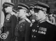 a group of men in military uniforms are standing in a line with a tp logo in the corner