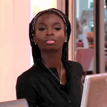 a woman wearing a head scarf and a necklace is sitting in front of a computer .
