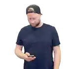 a man wearing a hat and a blue shirt is talking on a cellphone