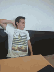 a man wearing a california t-shirt sits at a desk
