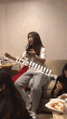 a woman is sitting on a couch with a plate of food in front of her and the word nutella is on the wall behind her