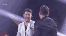 two men are hugging each other on a stage with rtve written on the bottom
