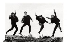 four men in suits are jumping in the air