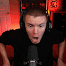 a man wearing headphones and a black shirt is sitting in front of a microphone .