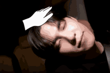 a hand is touching a man 's forehead with a black background
