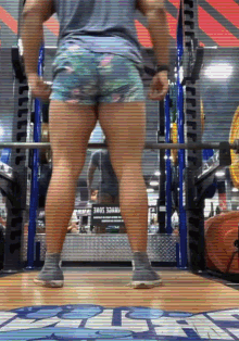 a person squatting in a gym with a sign that says 3ama on it