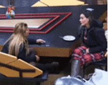 two women are sitting at a table with a plate of food on it .