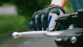 a person wearing a pair of gloves is holding the brake lever of a motorcycle