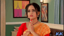 a woman wearing a yellow saree and a red blouse praying