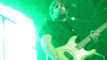 a man playing a guitar with a green background