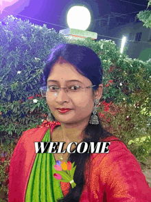 a woman wearing glasses stands in front of a sign that says " welcome "