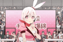 a girl with bunny ears stands in front of a crowd with chinese writing