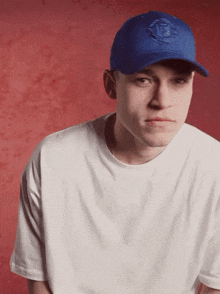 a man wearing a white shirt and a blue hat with the letter t on it
