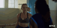 a woman in a sports bra is standing next to another woman in a blue shirt with netflix written on the bottom right