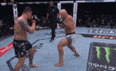 two men are fighting in a ufc ring with a monster energy drink in the foreground