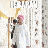 a man wearing a pink turban is walking down a hallway with lebaran written on the bottom