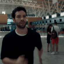 a man in a black shirt stands in a busy airport