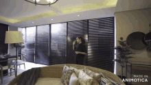 a woman stands in a living room with the words made in animotica on the bottom right