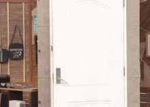 a white door with a blue handle and a bag that says ' i love you ' on it hangs on a wall