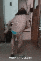 a woman in a bikini is dancing in a kitchen with the words mornin ' fucker written on the bottom .