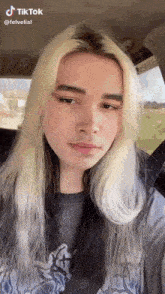 a young man with blonde hair is sitting in a car .
