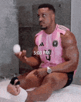 a man is sitting in a bathtub holding a ball in his hand .