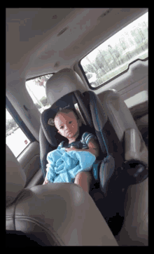 a baby is sitting in a car seat with a blue blanket on his lap
