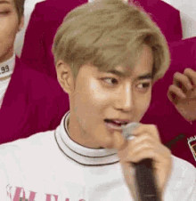 a young man is holding a microphone in his mouth while wearing a white shirt .