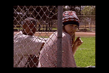 a man and a woman are behind a chain link fence in a park