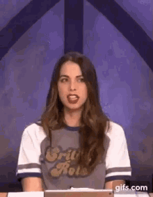 a woman is sitting at a table wearing a t-shirt that says `` britain rolls '' .