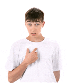 a young man in a white t-shirt is pointing at his chest