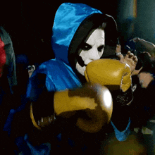 a person wearing a mask and a blue jacket is holding a yellow glove