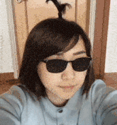 a woman wearing sunglasses and a ponytail looks at the camera