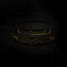 a glowing neon sign of a sandwich against a black brick wall