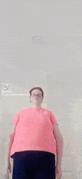 a woman in a pink shirt is standing in a room .